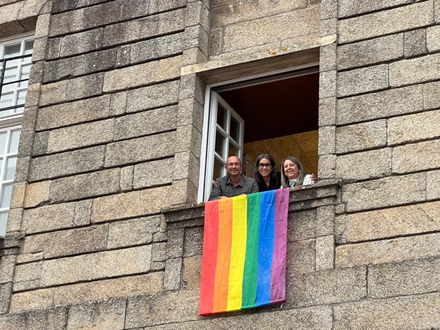 IMG Mercedes Roson Gonzalo Muinos e Mila Castro desde a xanela do despacho das Non Adscritas coa bandeira LGTBIQ