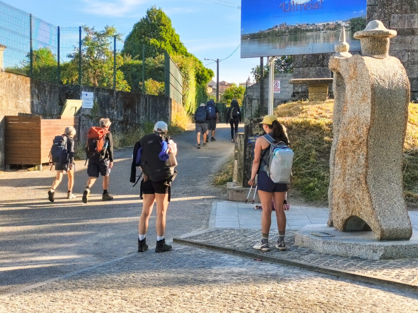10072026 Peregrinos na rua Olimpicos Tudenses xunto a nova escultura de Rai